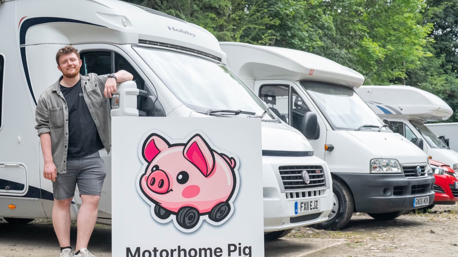 A row of motorhomes and campervans parked up for sale beside the Motorhome Pig sign