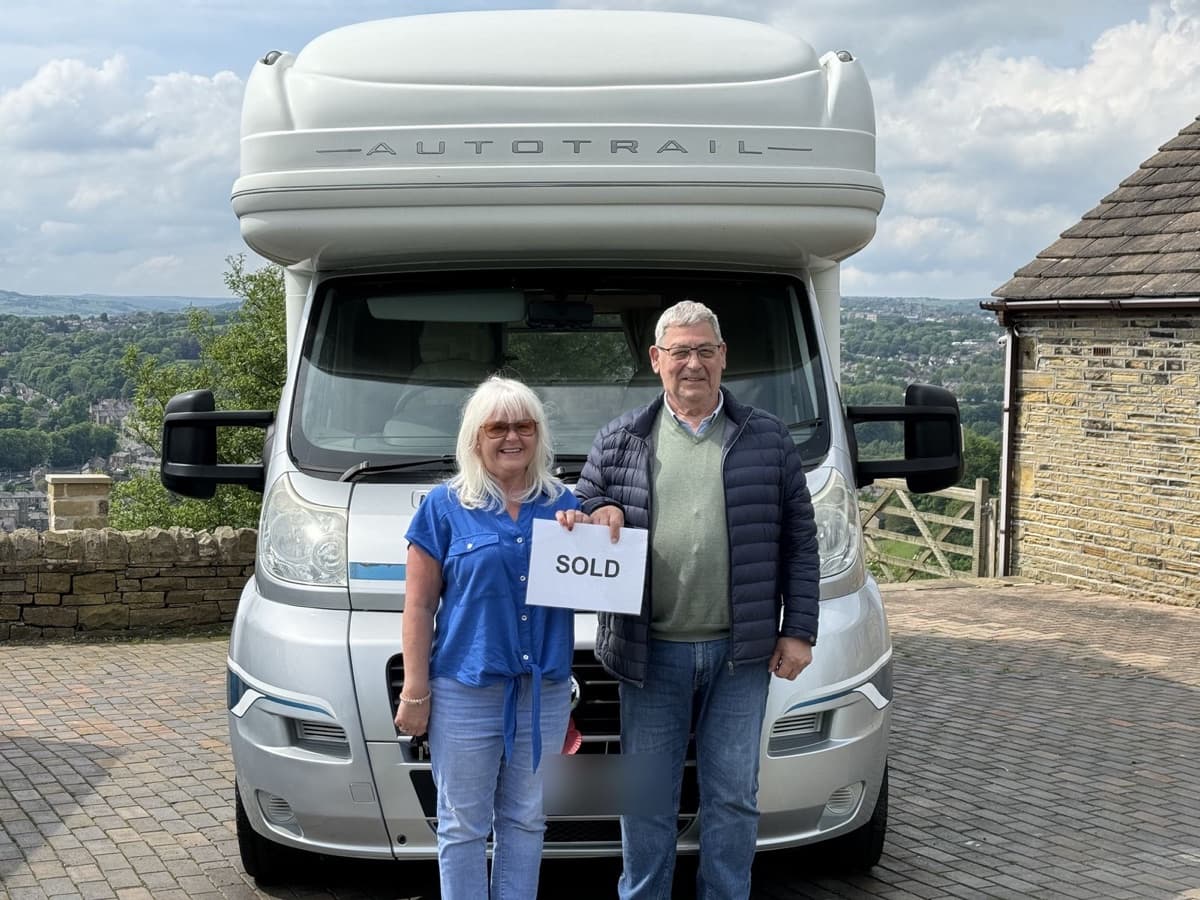 Owners holding a SOLD sign in front of their Auto-Trail motorhome
