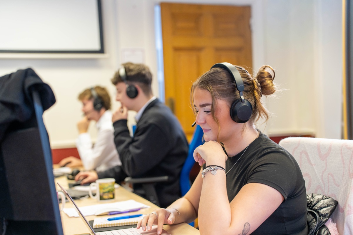 Three Motorhome Pig team members wearing headsets, working at computers in the company's Halifax office