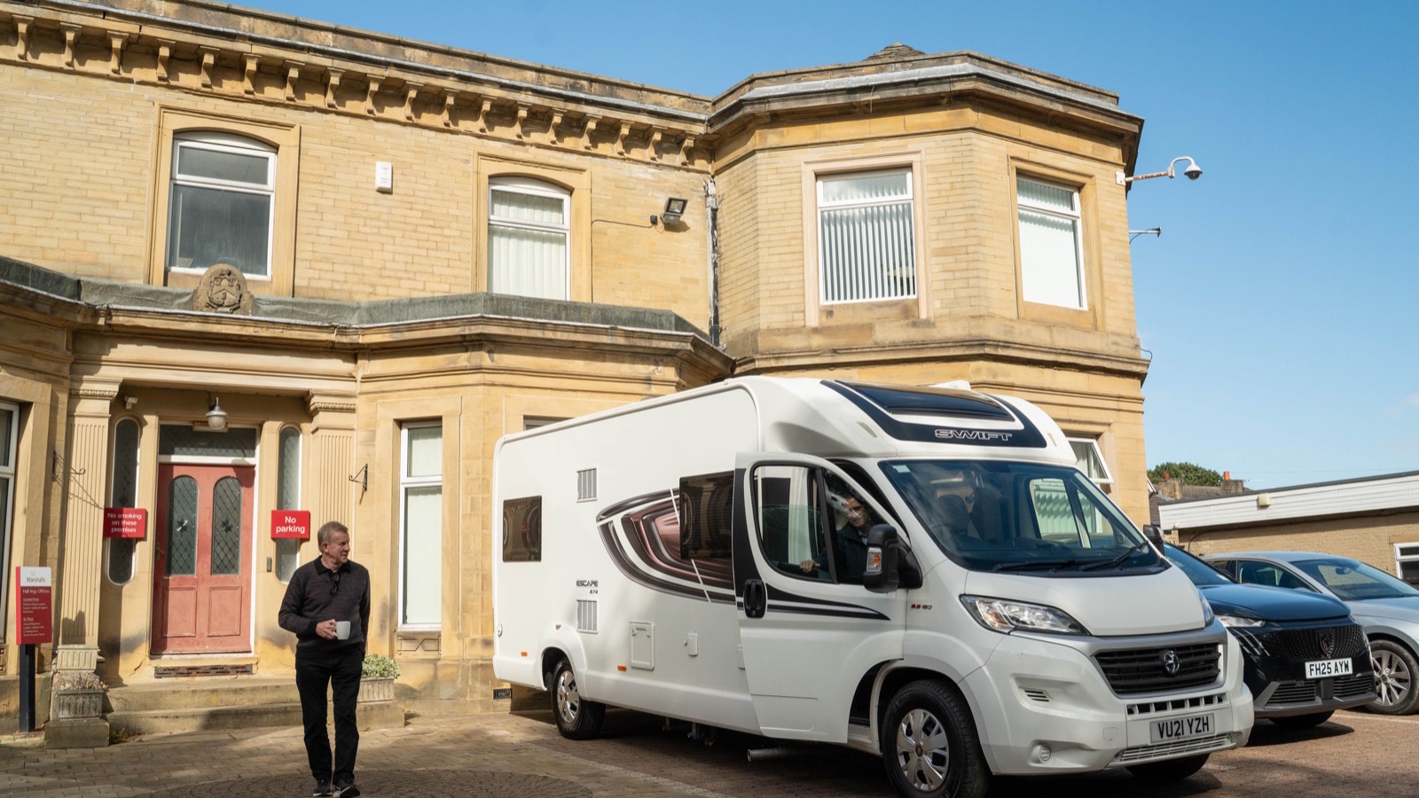 A white coachbuilt motorhome parked on the forecourt outside Motorhome Pig’s stone office building in Halifax