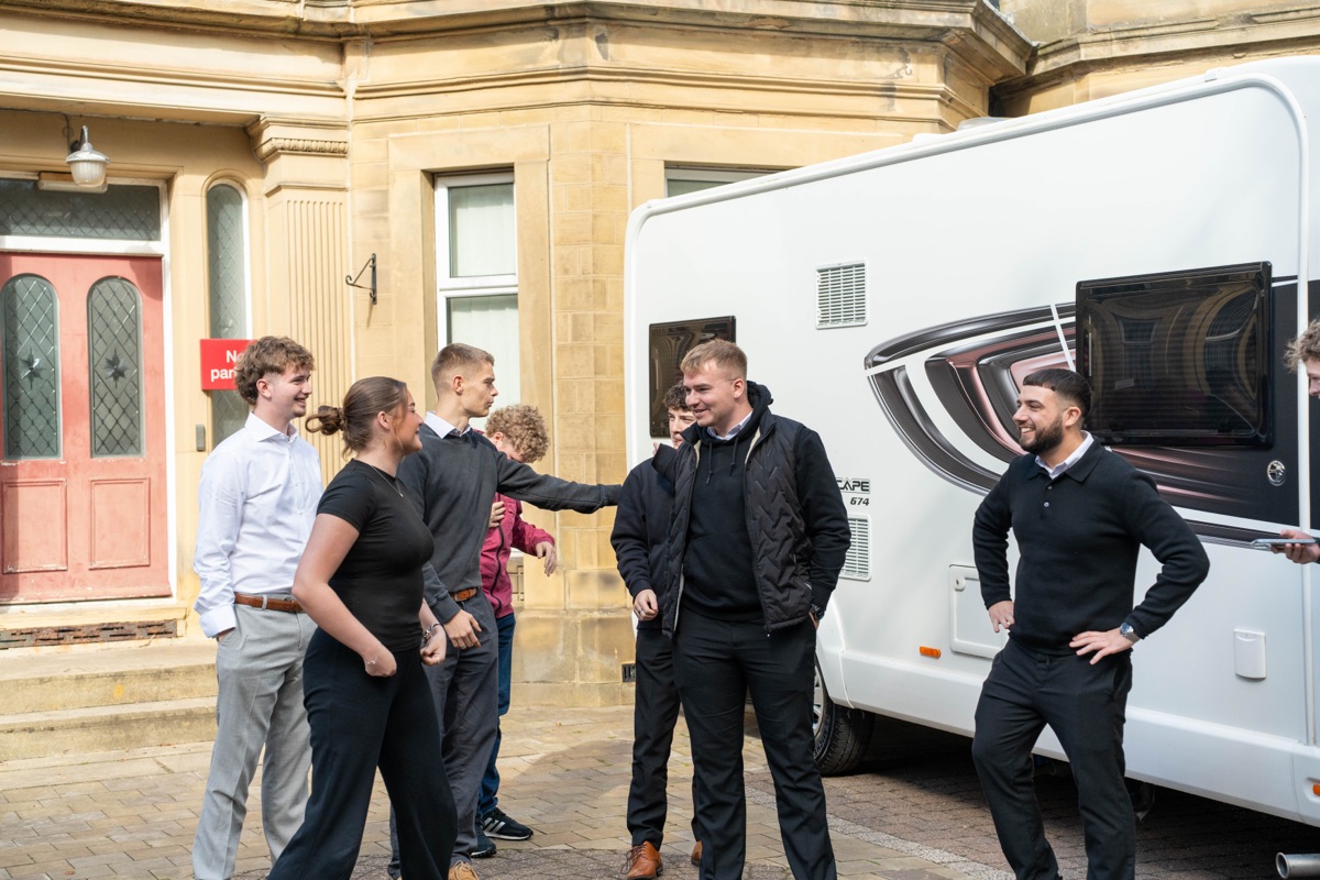 Motorhome Pig team members laughing together outside the office, next to a white motorhome