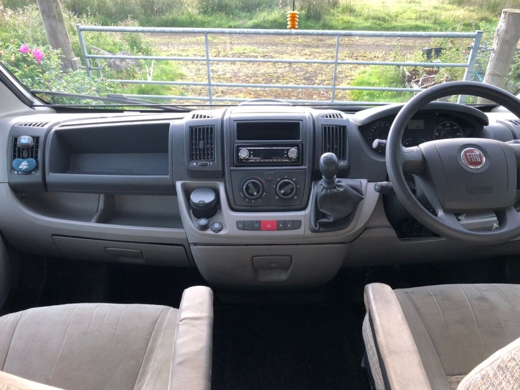The Fiat Ducato cab of the Autocruise Rhythm, showing the steering wheel, dashboard and twin cab seats