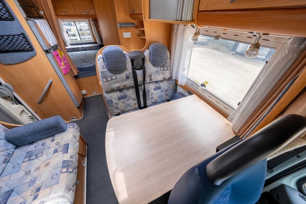 The front lounge of the Chausson Welcome 85 with swivel captain's seats, a table and blue upholstery