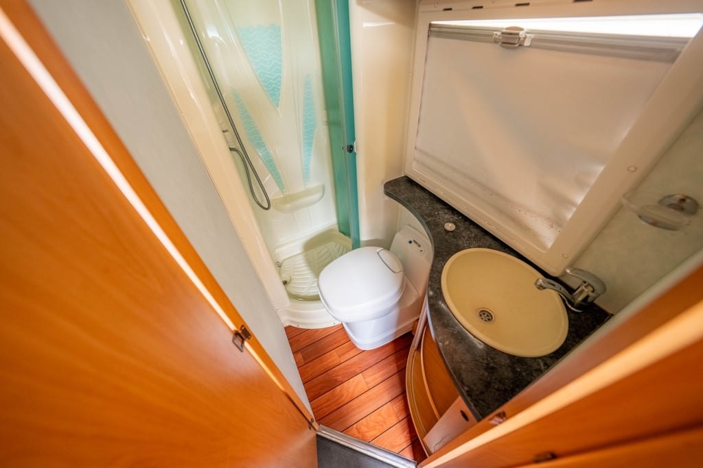 The washroom of the Chausson Welcome 85 with toilet, wooden floor and a folding door