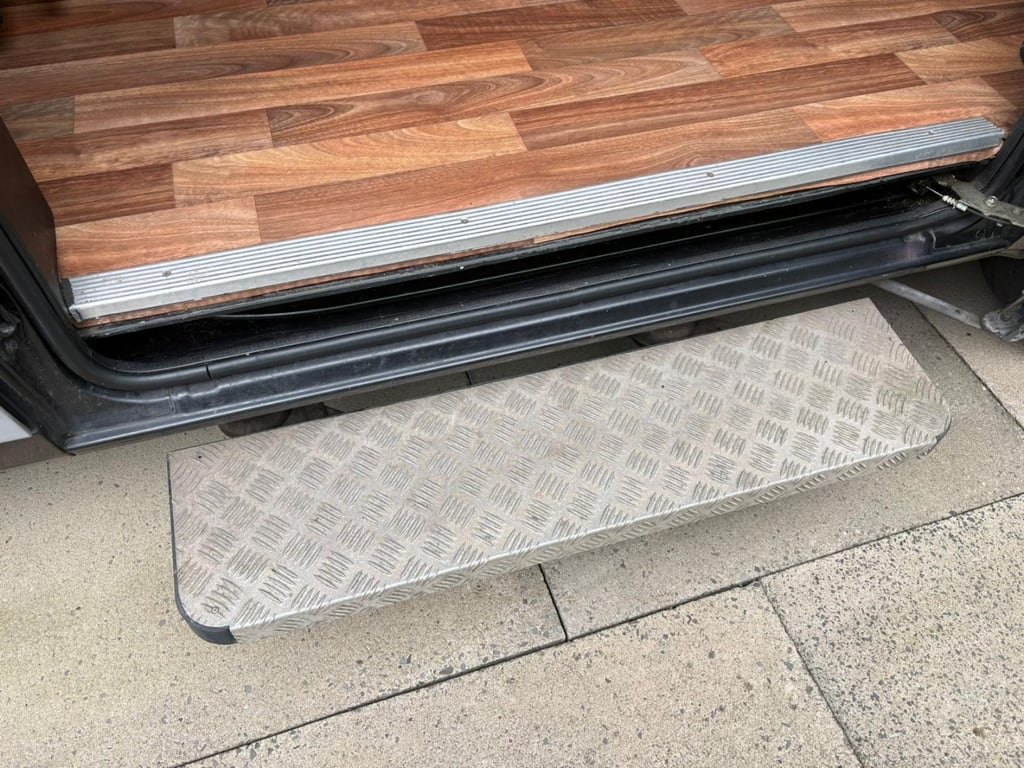 The automatic step extended from the side door sill of the campervan onto a block-paved driveway