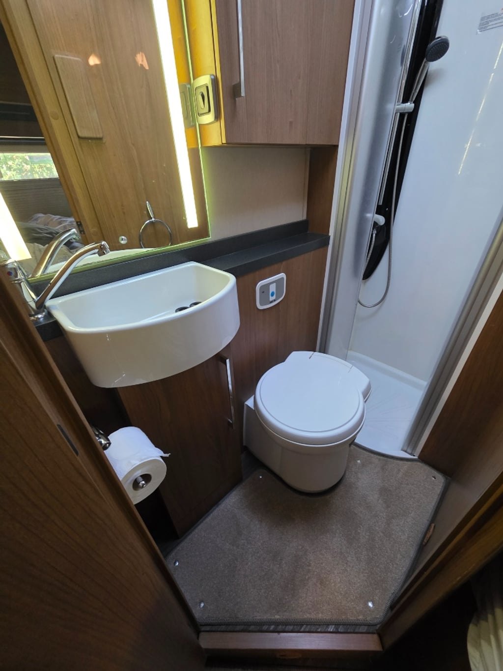 The washroom of the Auto-Trail Cherokee with a wall-hung basin, a mirrored cabinet, a cassette toilet and a separate shower cubicle to the right