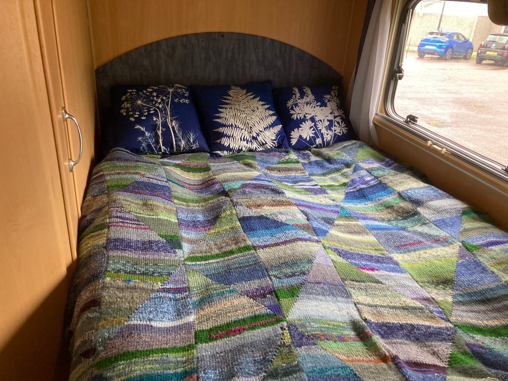 The rear French island bed of the Auto-Roller 15 made up with a patterned quilt and cushions