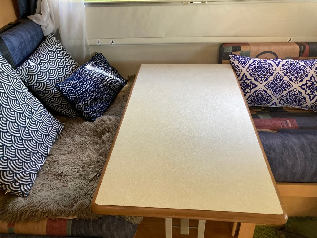 The dinette of the Roller Team Auto-Roller 15 with the table up and cushions arranged along the seating
