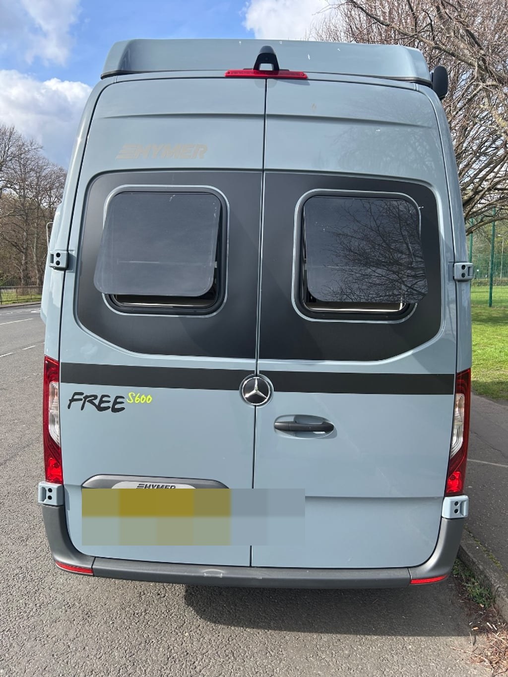 Rear view of the grey Hymer Free S 600 campervan showing the Hymer and 'FREE S 600' badging and Mercedes-Benz rear doors (number plate digitally obscured)