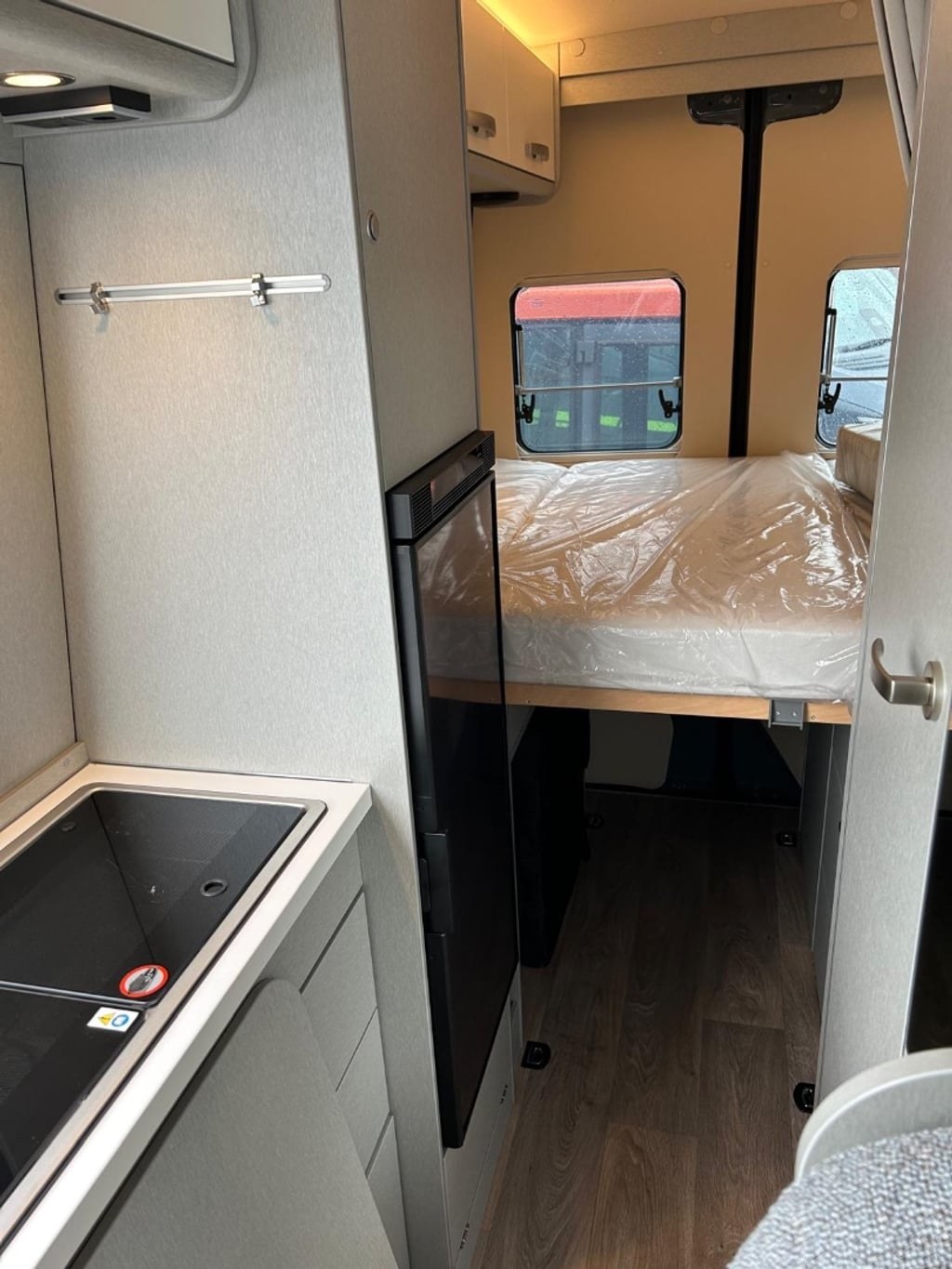 Interior of the Hymer Free S 600 showing the galley kitchen, fridge and the rear bed with the mattress still wrapped in factory plastic