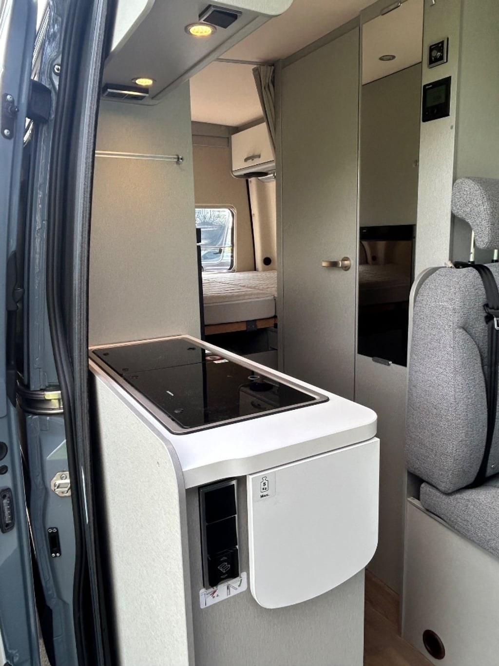 The bright galley kitchen of the Hymer Free S 600 with an induction hob and sink, looking through to the rear fixed bed