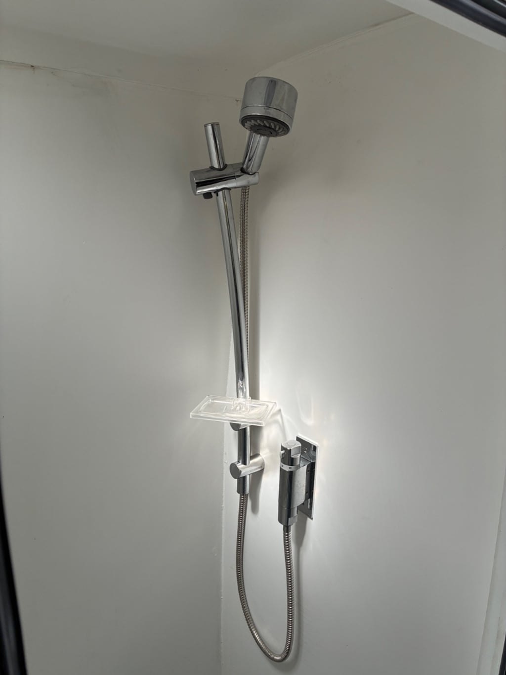 The interior of the campervan's wet room showing a wall-mounted shower head and rail